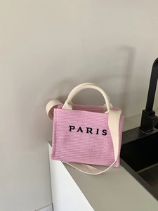 Detailed shot of pink knitted mini tote with black Paris embroidery on a white surface
