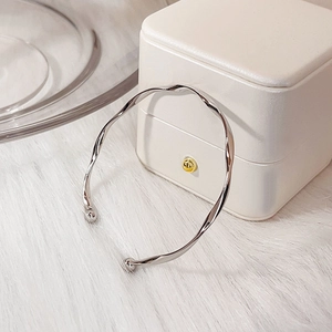Elegante bracciale rigido Mobius argento ritorto su portagioie e tappetino di peluche