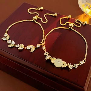 Dettaglio di bracciali dorati regolabili con zirconi marquise e occhio di gatto su legno