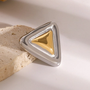 Close-up of geometric triangular brooch in gold and silver finish on a stone pedestal
