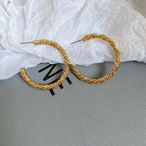 Close-up of golden twisted hoop earrings with elegant spiral texture on white background