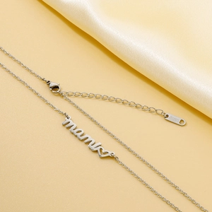Close-up of silver mama pendant necklace with heart on yellow silk fabric background