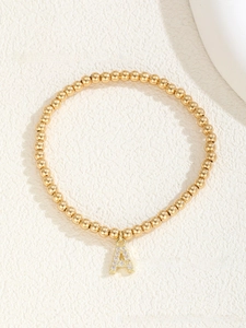 Detail of beaded bracelet with gold plating and sparkling letter A initial pendant