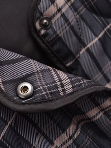 Détail macro du tissu à carreaux matelassé et bouton-pression en métal sur la veste