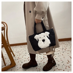 Detail of black quilted nylon handbag featuring a plush white puppy patch and beige straps
