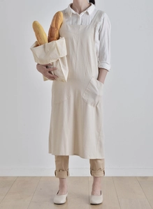 Detail view of beige cotton linen apron with two large front pockets in home setting