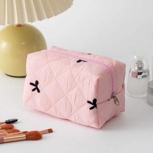 Detailed view of pink quilted cotton lipstick pouch with black bow pattern and zipper