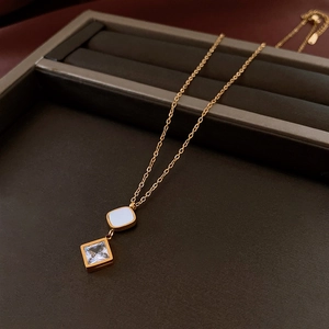 Detail showing gold necklace with square pearl and cubic zirconia gemstone pendants