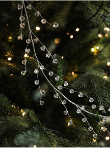 Close-up of sparkling clear crystal bead pendant hanging on a decorated Christmas tree branch