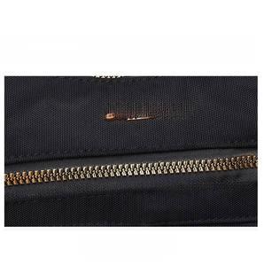 Detail of premium gold metal zipper and brand logo on waterproof black nylon bag