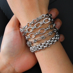 Detail of five silver-toned stainless steel chain bracelets layered on a model's wrist