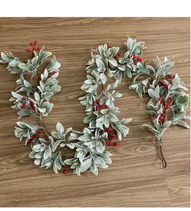 Close-up of Christmas garland with velvet rabbit ear leaves and red berries on wood