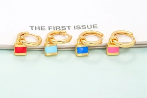 Macro shot of colorful enamel padlock earrings with gold metal rings and charms