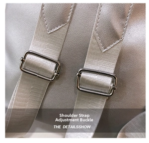 Detail view of adjustable silver metal buckle and litchi texture leather strap on backpack