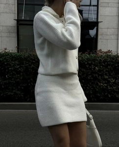 Vue de rue d'un ensemble deux pièces en tricot blanc avec cardigan à revers et jupe midi