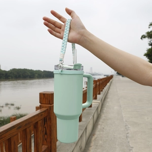 Close-up of mint green 40oz tumbler with a blue and white woven carry handle strap