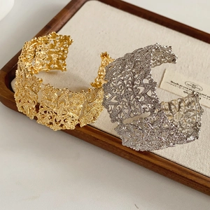 Detailed view of wide hollow-out pattern bangles in gold and silver metal finishes