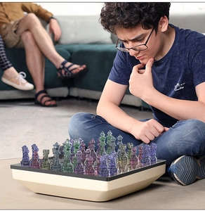 A young boy playing with transparent purple and green resin chess pieces on a floor
