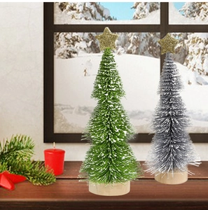 Mini desktop Christmas trees with snow effect and wooden base on a wooden table