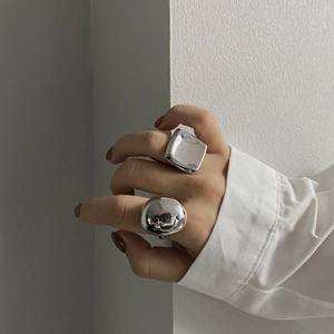 Close-up of polished silver geometric sphere and square rings with a mirror finish
