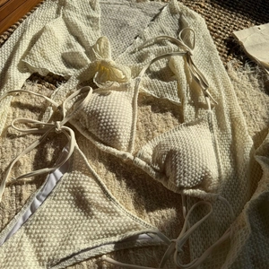 Dettaglio del bikini a tre pezzi bianco crema con trama a nido d'ape e copricostume mesh