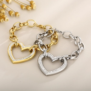 Detailed view of gold and silver chunky chain bracelets with crystal heart pendants