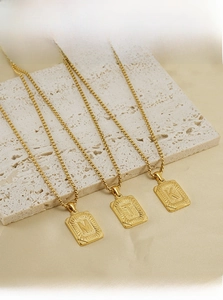 Macro detail of 18K gold-plated stainless steel letter pendant on square box chain