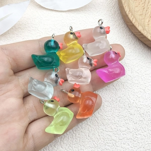 Colorful luminous resin duck charms for DIY jewelry making held in palm for scale