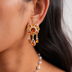 Detailed close-up of a vintage-style gold earrings with amber stones and water drop charms