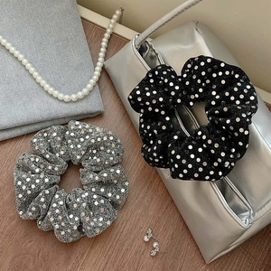 Sparkly sequin scrunchies set in silver and black colors on a wooden surface