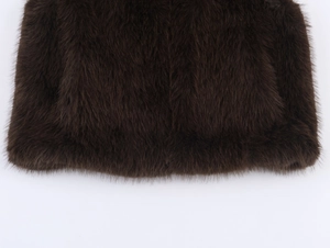 Macro detail of high-density dark brown faux fur texture and smooth hem on vest