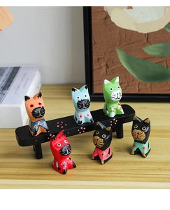 Detailed view of six colorful hand-painted wooden cats on a mini black wooden bench