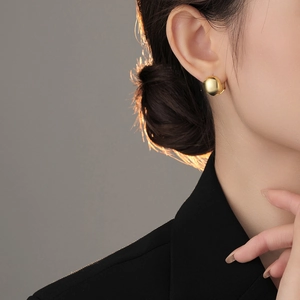 Close-up side view of a model wearing minimalist polished gold ball stud earrings