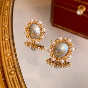 Detail of vintage oval blue stone earring with pearl border reflected on mirror