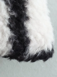Close-up of the soft black and white plaid faux fur texture on a long winter coat