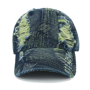 Close-up of distressed dark blue washed denim baseball cap with heavy ripped details