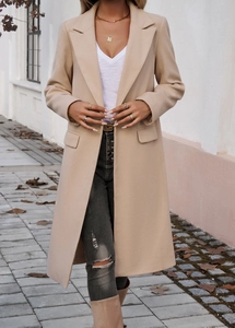 Detail view of beige long-line wool coat with notch lapels and flap pockets worn outdoors