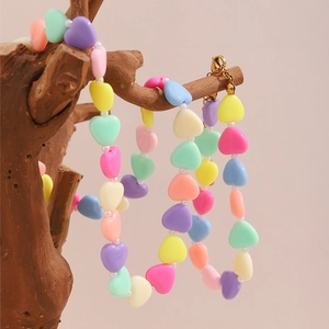Close-up of colorful heart-shaped acrylic beads on a necklace with golden metal clasp