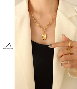 Detail of gold double-layer necklace with irregular texture pendant on stainless steel