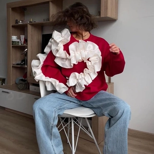 Détail d'un sweat rouge avec de grands volants blancs sur les épaules et le buste