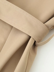 Detailed macro view of khaki twill fabric texture and stitched belt loop on the trench coat