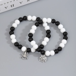 Detailed close-up of couple bracelets with black white beads and silver spider charms