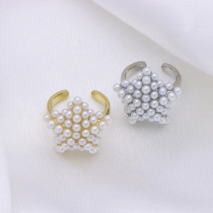 Detail of gold and silver adjustable rings with star-shaped pearl settings on silk