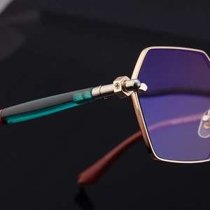 Close-up of golden polygonal frame hinges with nut-shaped hardware and green temples