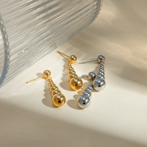 Detail of gradient metal ball drop earrings in polished gold and silver stainless steel