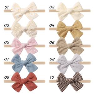 Flat lay collection of ten baby bow headbands in various colors and floral patterns