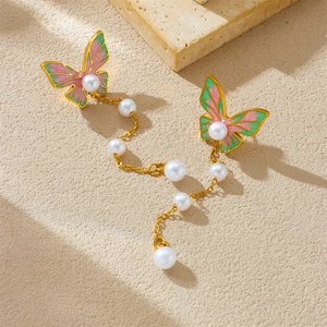 Chic butterfly pearl earrings with pink and green enamel tassels on stone background