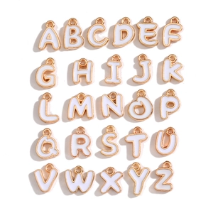 Flat lay of 26 pieces gold-plated alloy alphabet pendants with white enamel for DIY jewelry