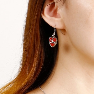 Détail des boucles d'oreilles cœur argent avec émail rouge et gravure Love sur mannequin