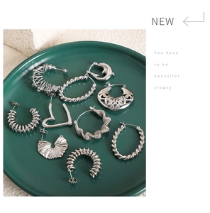 Flat lay of retro hollow silver earrings on green tray with elegant stone background
